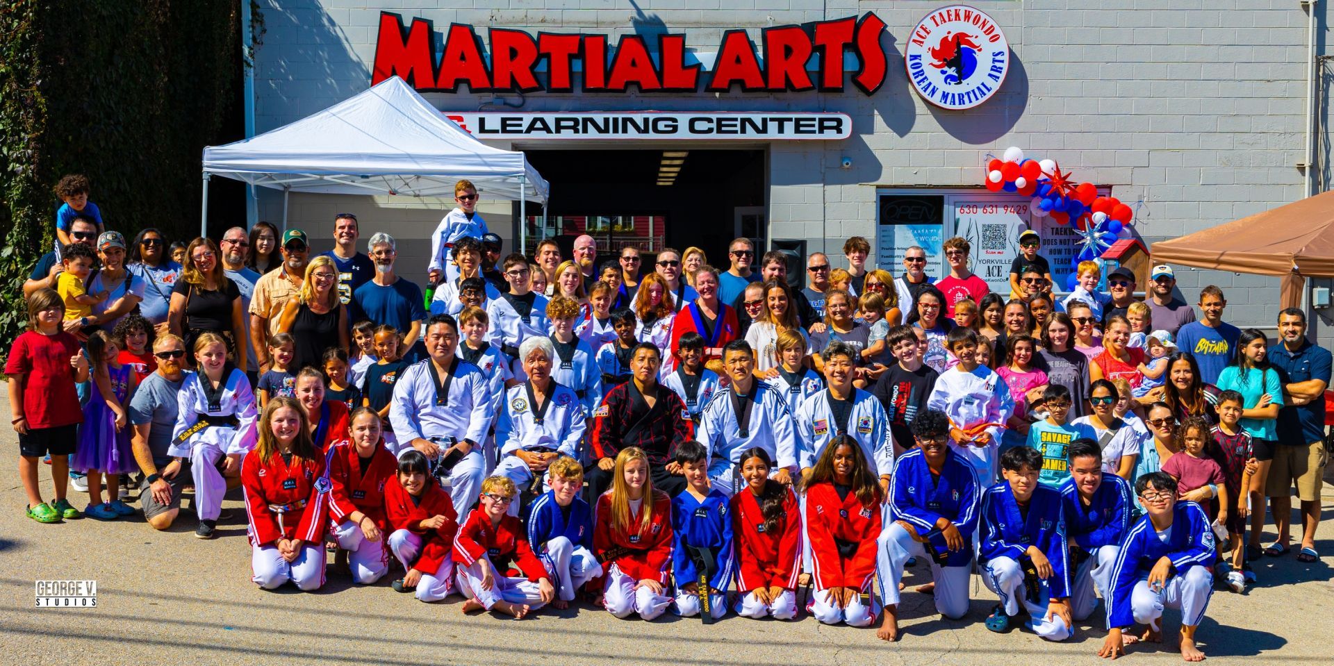 Large group of ACE students in uniform with families and instructors outside the school in Yorkville