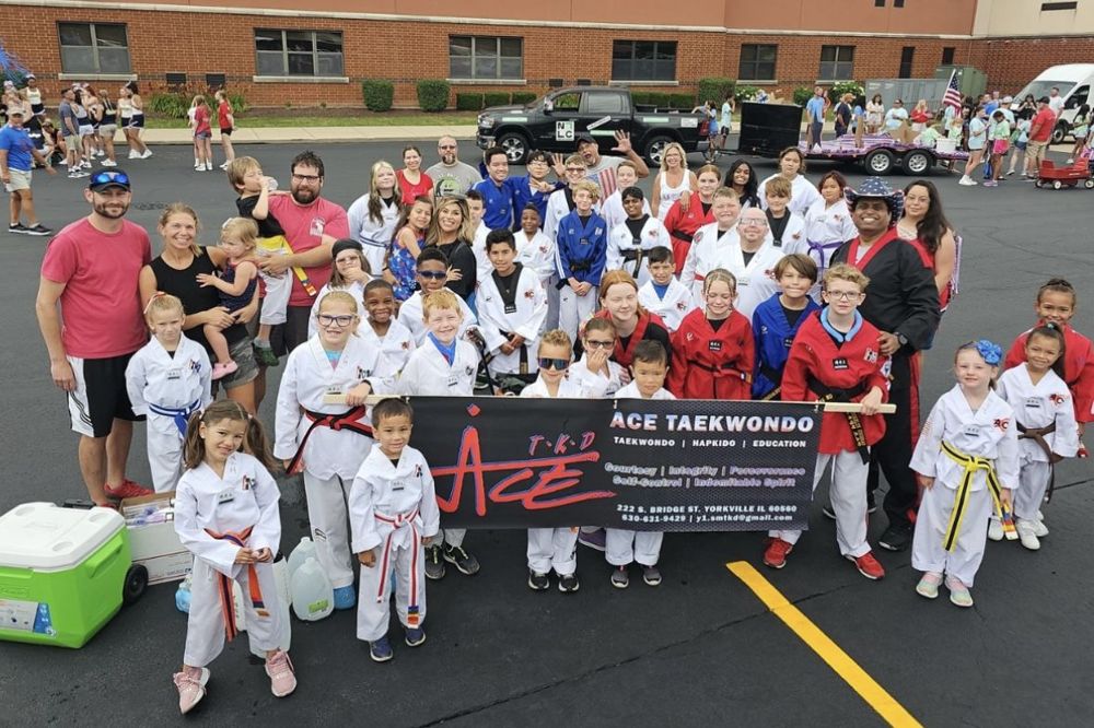 ACE students and families with an ACE Taekwondo banner at a community event